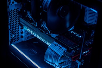 A detailed view of a computer's interior showcasing components such as a graphics card, cooling fans, and neatly arranged cables. The image features low lighting with a prominent blue LED glow highlighting the hardware.