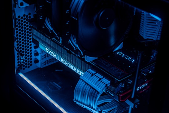 A detailed view of a computer's interior showcasing components such as a graphics card, cooling fans, and neatly arranged cables. The image features low lighting with a prominent blue LED glow highlighting the hardware.