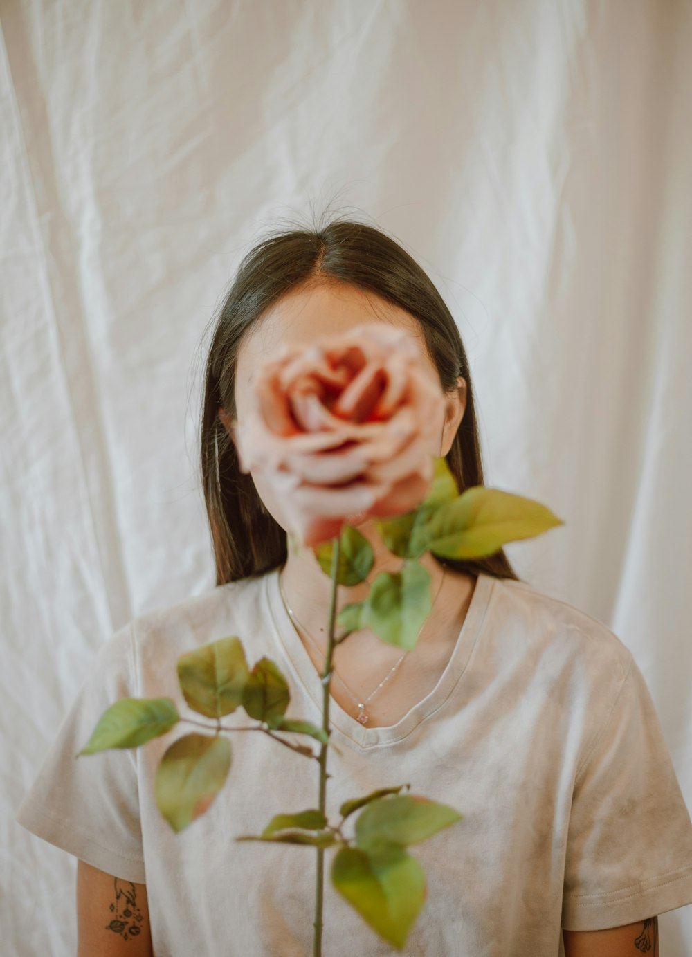 woman in gray crew neck shirt covering her face with her hand