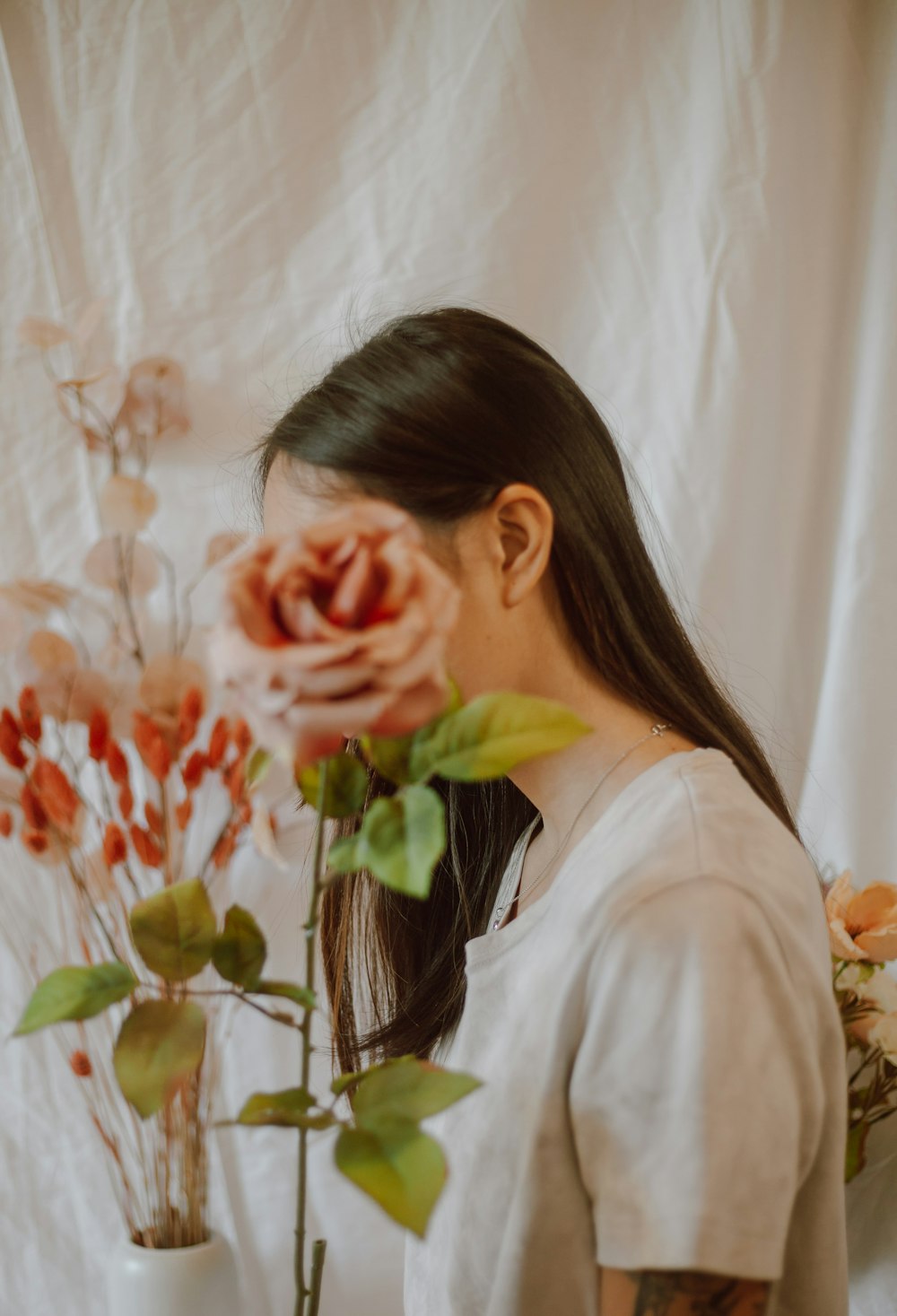 woman in white shirt covering her face with her hands