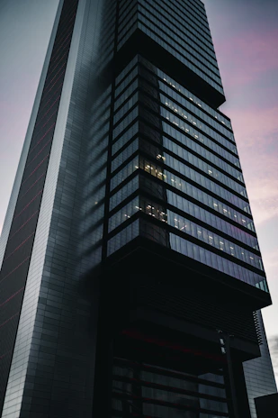 A sleek matte black skyscraper reflecting golden sunset hues, symbolizing power and prestige.