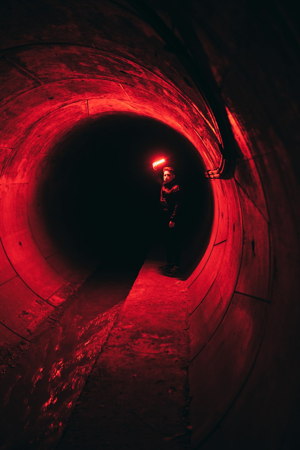 man in black jacket walking on tunnel