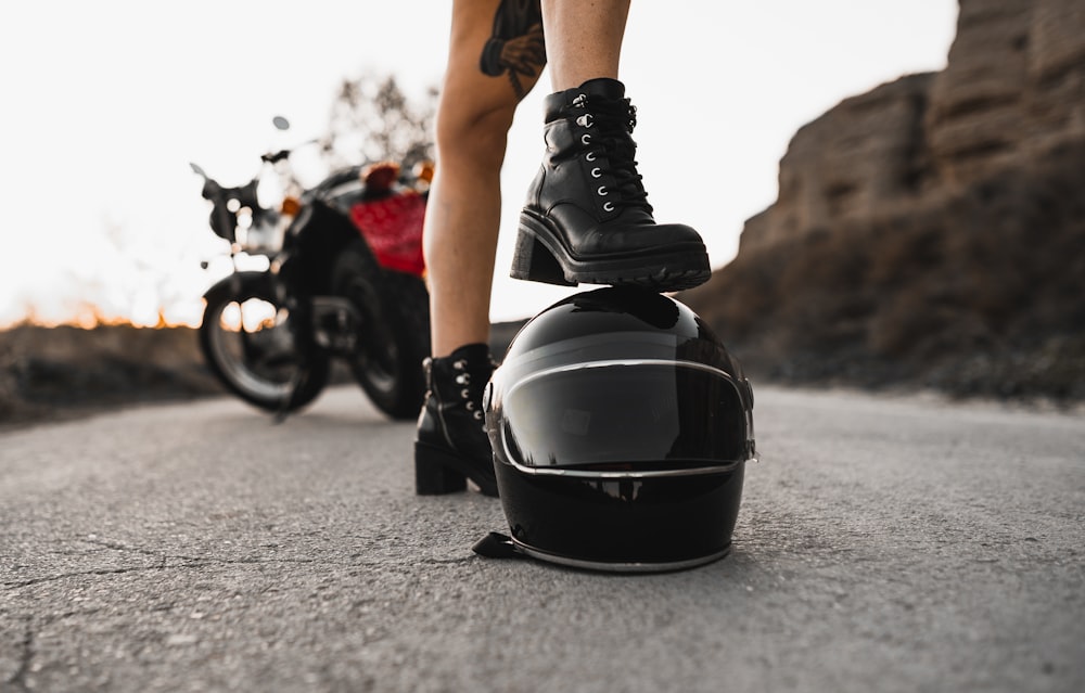 person in black leather boots and black helmet riding motorcycle