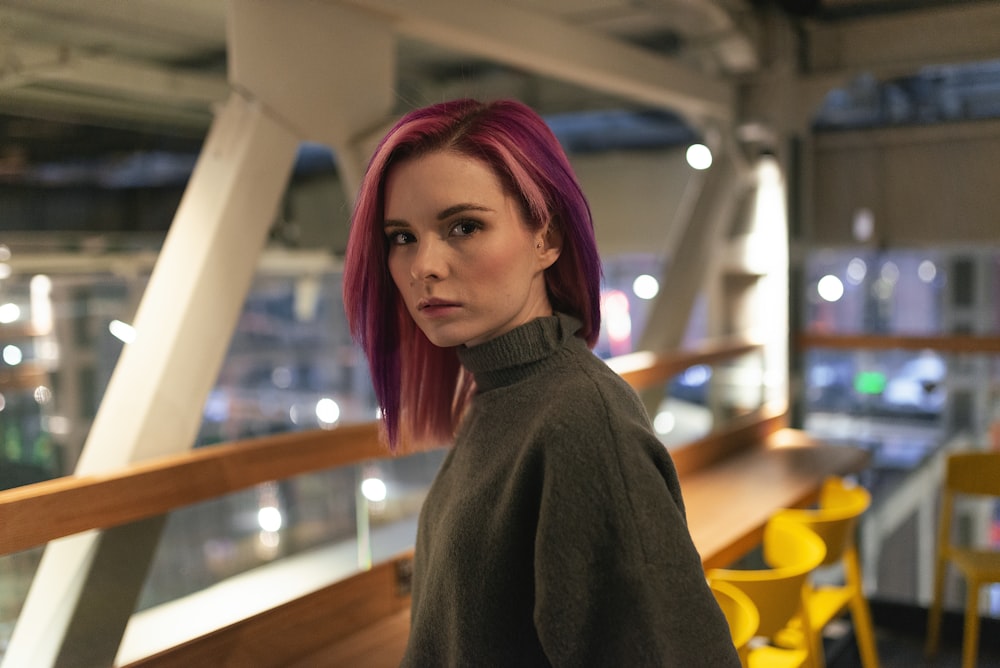 woman in gray sweater standing near brown wooden table