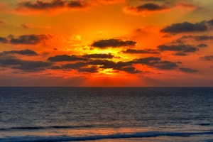 body of water under cloudy sky during sunset