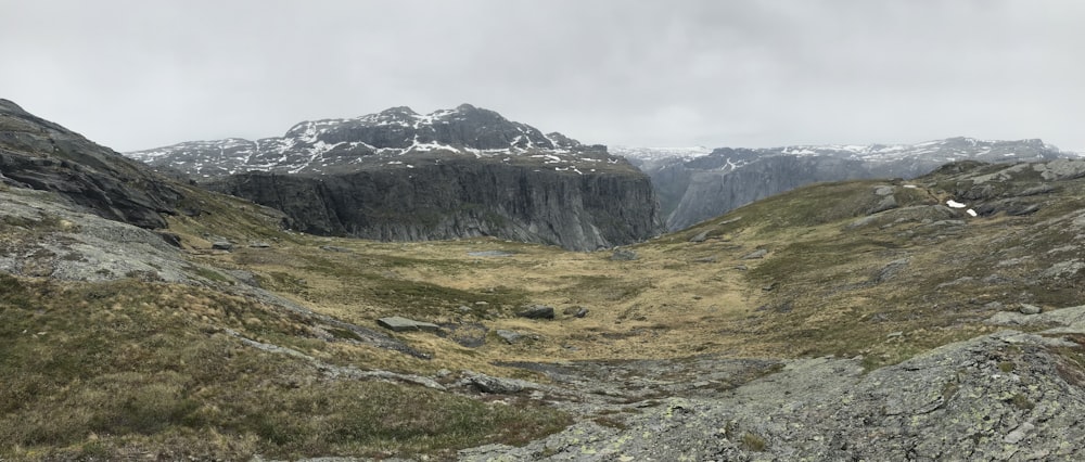 Grünes Grasfeld in der Nähe des Berges unter weißem Himmel tagsüber