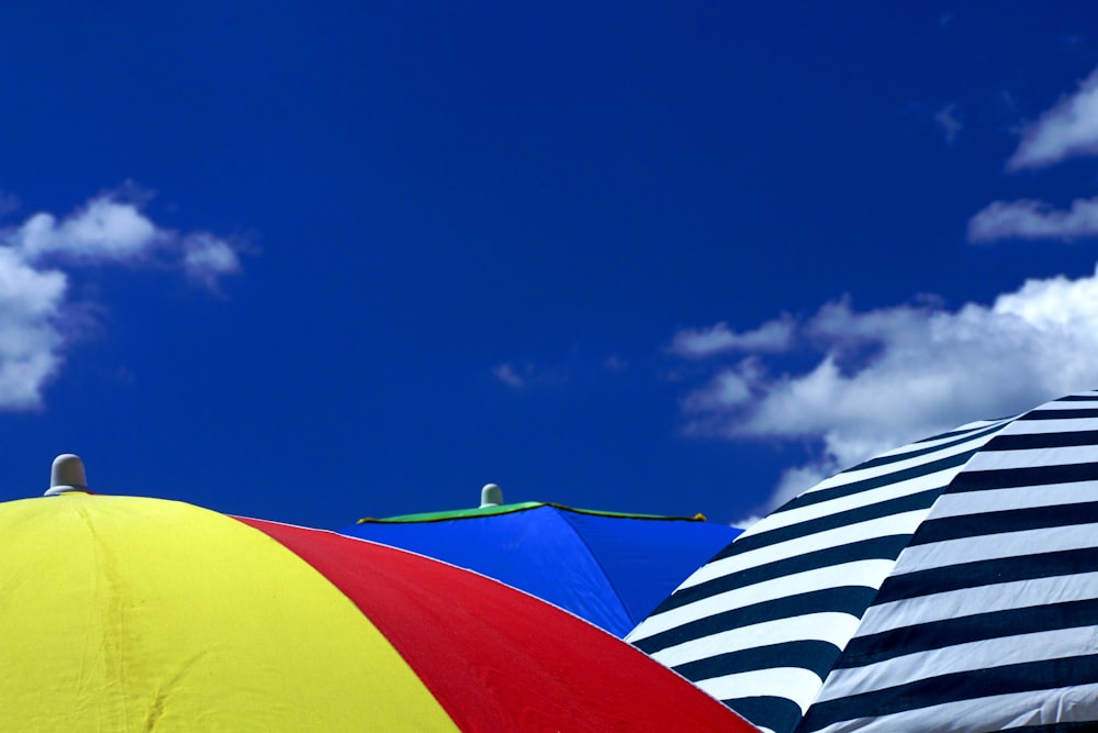 paraguas rojo, amarillo y azul bajo el cielo azul
