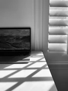Close-up shot of a sleek laptop open on a wooden desk with sunlight.
