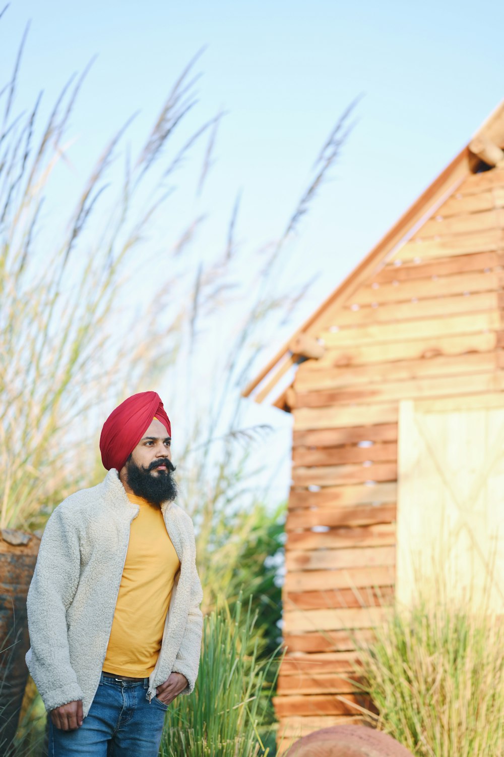 woman in red hat and gray sweater standing beside brown wooden house during daytime