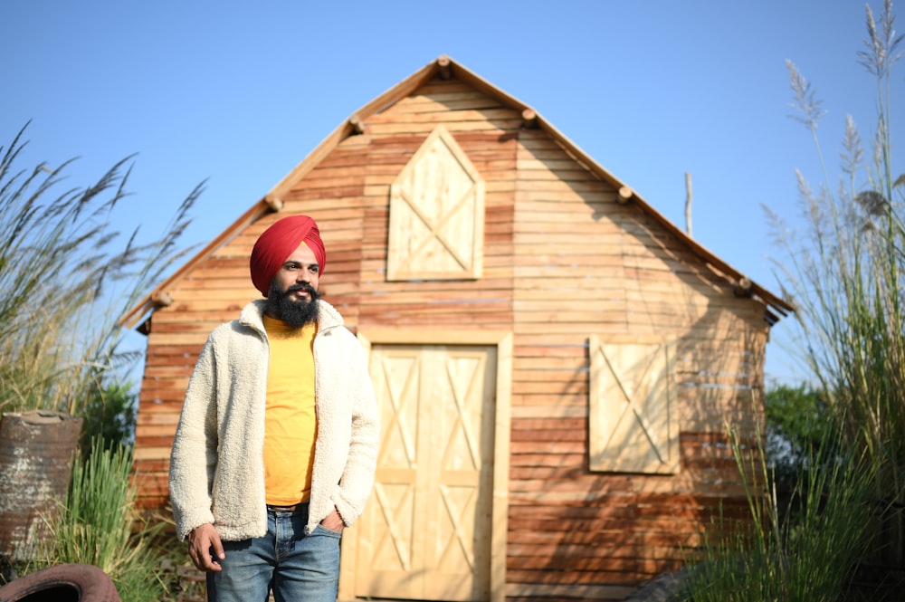 woman in white sweater and blue denim jeans standing beside brown wooden house during daytime