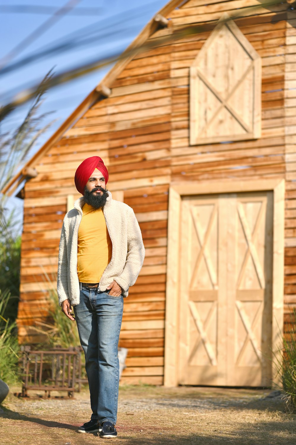 woman in white sweater and blue denim jeans standing near brown wooden wall during daytime