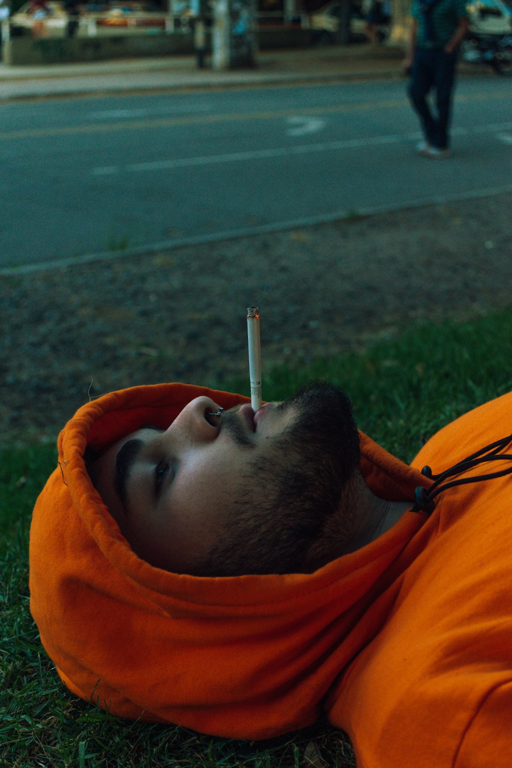 man in orange hoodie smoking cigarette