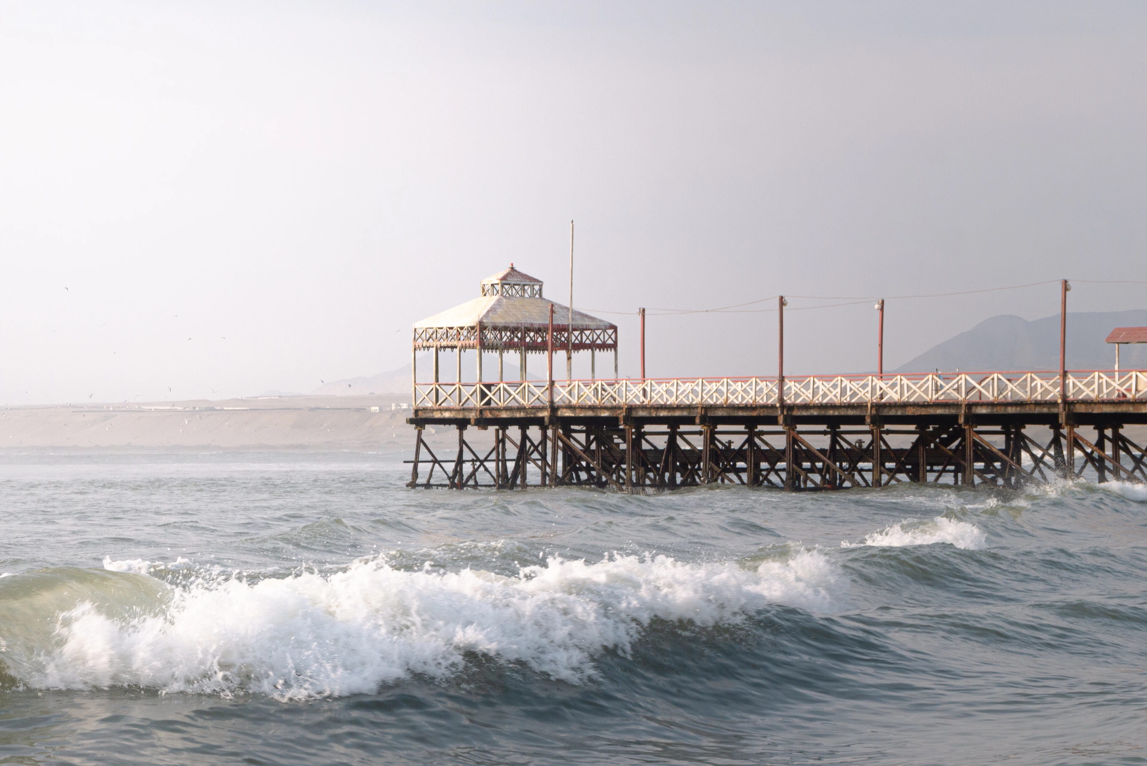 The wooden pier with its pavilion reaching into the surf at Huanchaco on a soft grey day