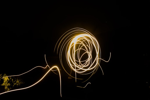 A swirling pattern of bright, golden light streaks against a dark background, creating an abstract and dynamic visual effect.
