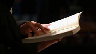 person reading book on black table