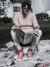 woman in pink knit sweater and white pants sitting on white plastic chair