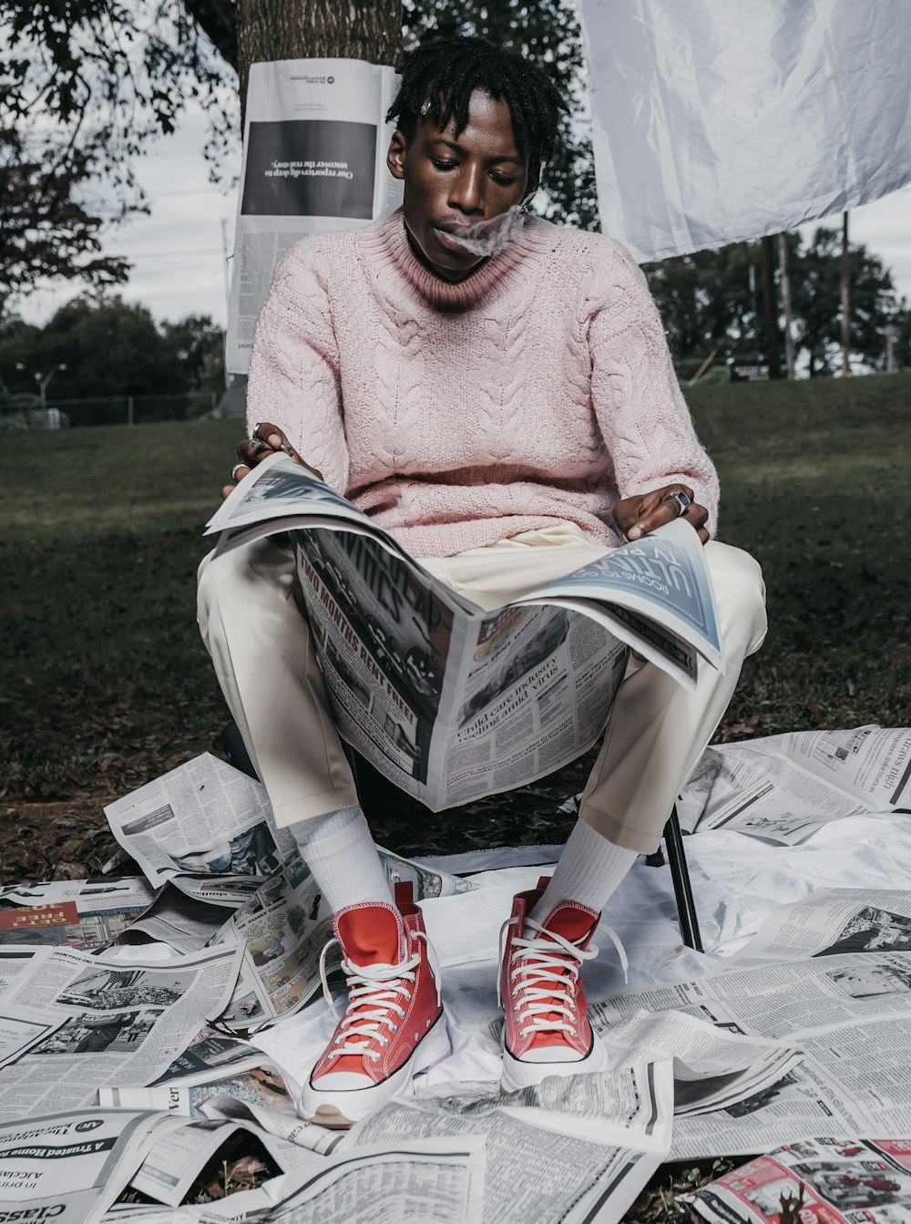 woman in pink knit sweater and white pants sitting on white plastic chair