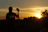 Smiling traveler holding a camera with a vibrant sunset backdrop on a safari trip.