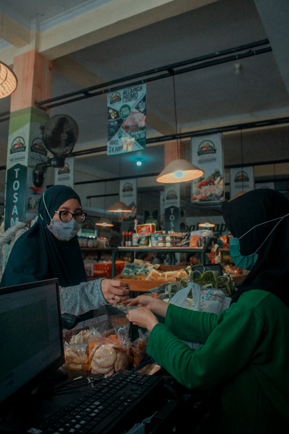 Mujer en camisa verde de manga larga de pie cerca de mujer en hiyab negro