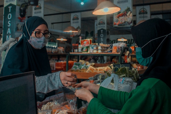 woman in green long sleeve shirt standing near woman in black hijab