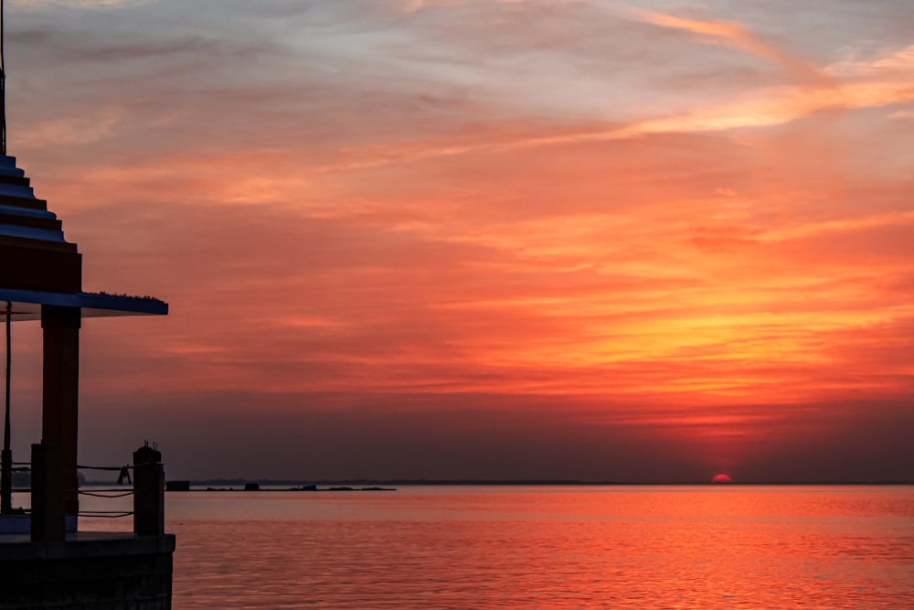 Silueta del faro cerca del cuerpo de agua durante la puesta del sol