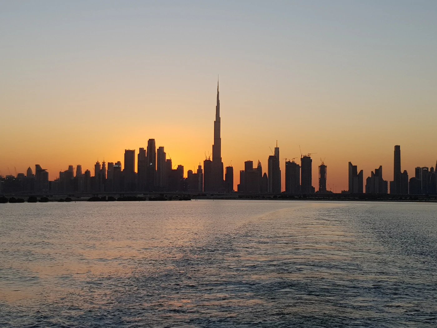 Dubai city skyline seen across the water at sunset