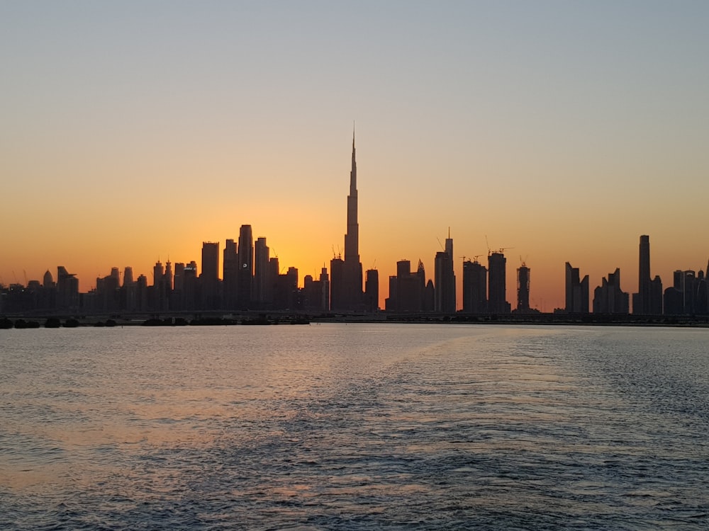 city skyline across body of water during sunset