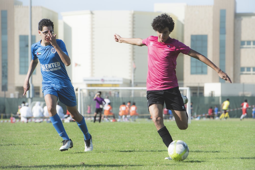 man in red shirt and black shorts playing soccer during daytime