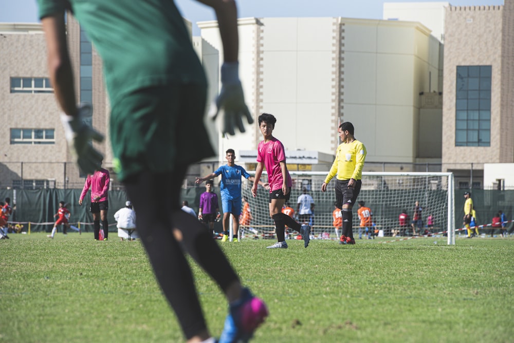 people playing soccer on green grass field during daytime