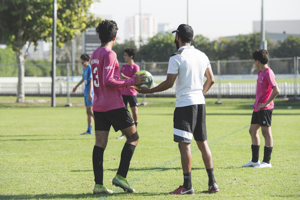 3 men playing soccer on green grass field during daytime