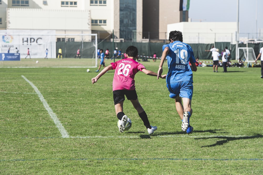 group of people playing soccer on green grass field during daytime