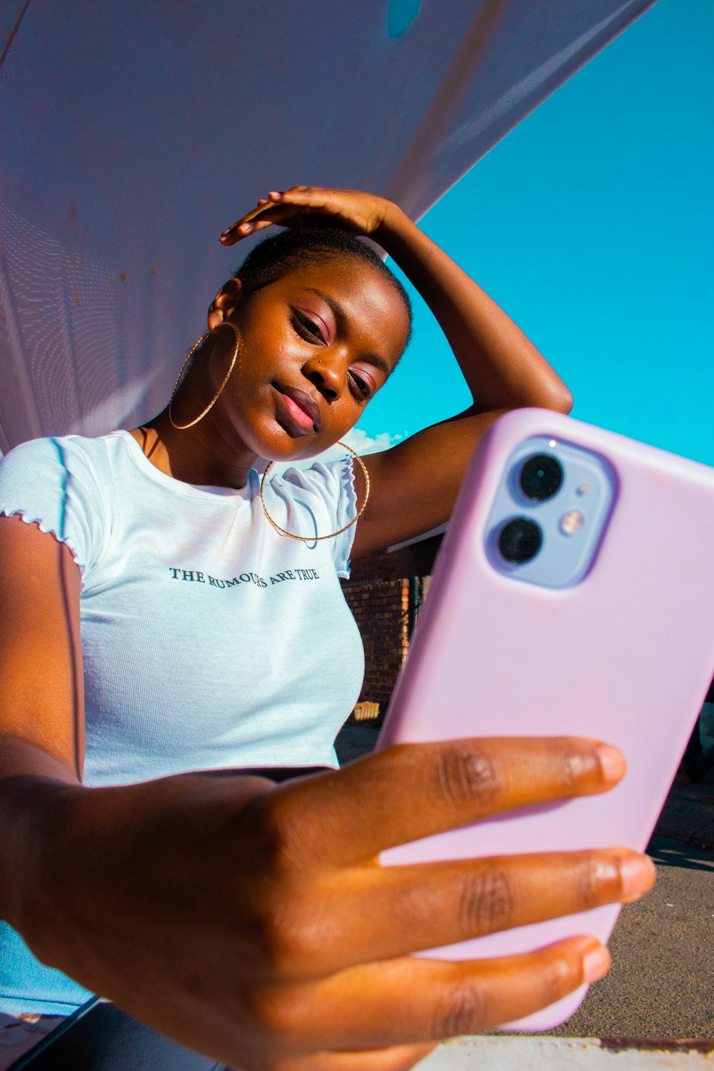 woman in white tank top holding white smartphone