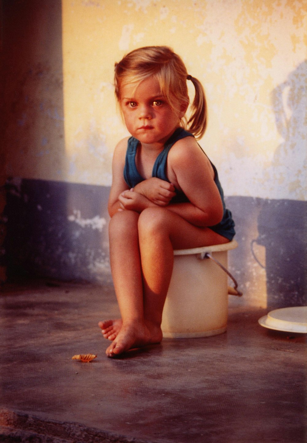 femme en débardeur bleu assise sur la cuvette de toilette en céramique blanche