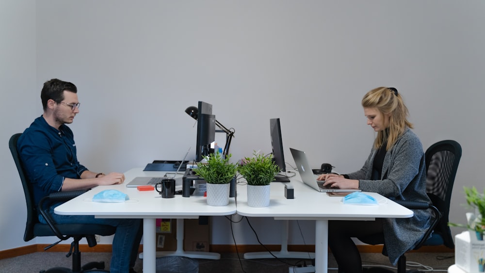 Mujer con blazer negro sentada a la mesa usando MacBook