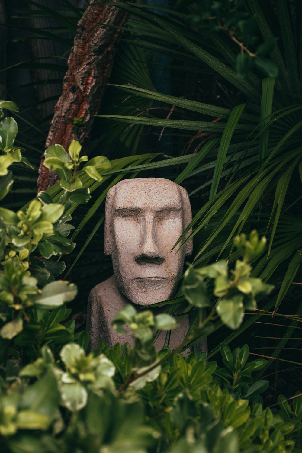 gray concrete statue near green leaves