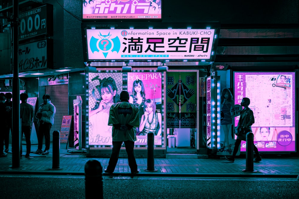 man in black jacket standing on sidewalk during night time