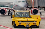 Technicians working on a sturdy aircraft towbar near a commercial jet.