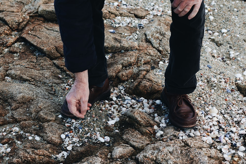 Persona con pantalones negros de pie en suelo rocoso durante el día
