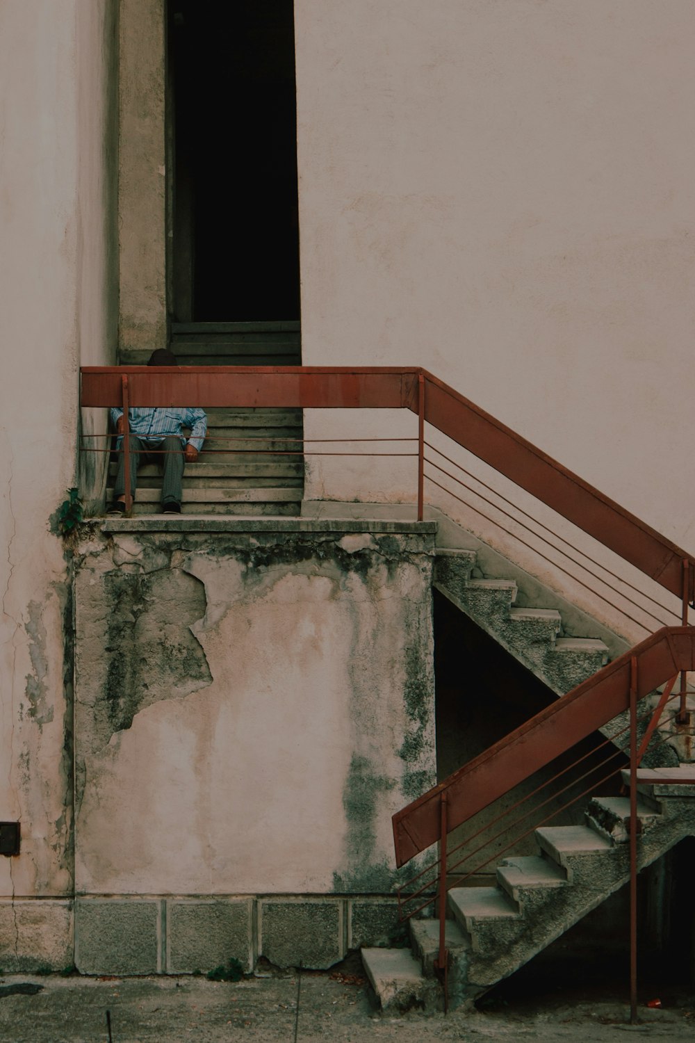 man in blue shirt sitting on concrete stairs