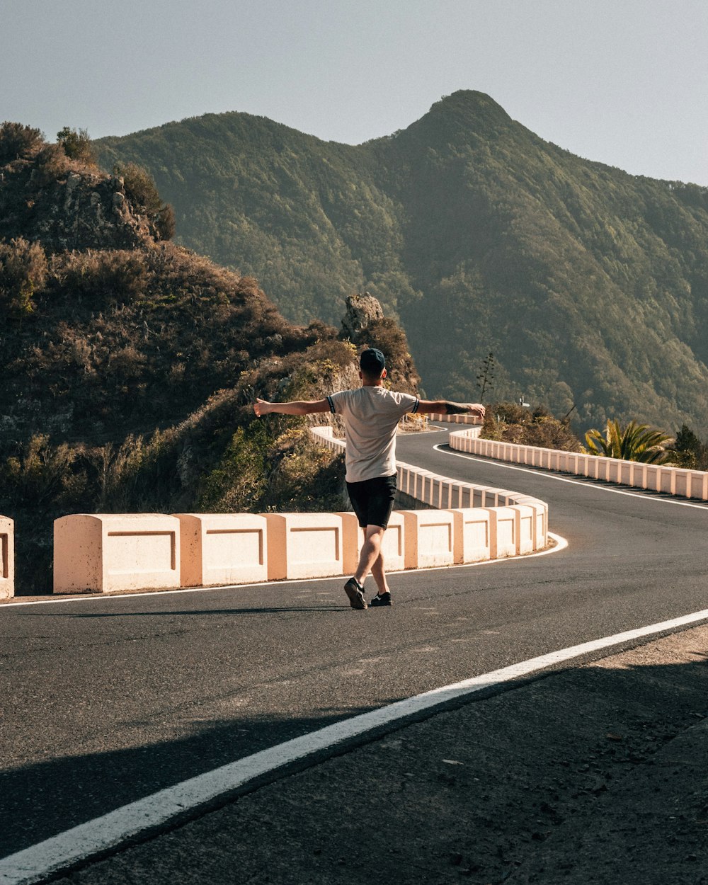 woman in white shirt and black pants walking on gray concrete bridge during daytime