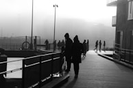 Silhouetted figures walking along a riverbank at dawn, mist rising in the background.