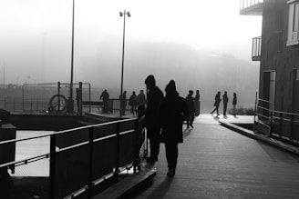 Silhouetted figures walking along a riverbank at dawn, mist rising in the background.