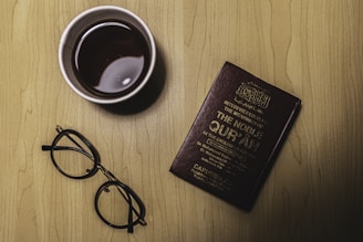 black framed eyeglasses beside purple book