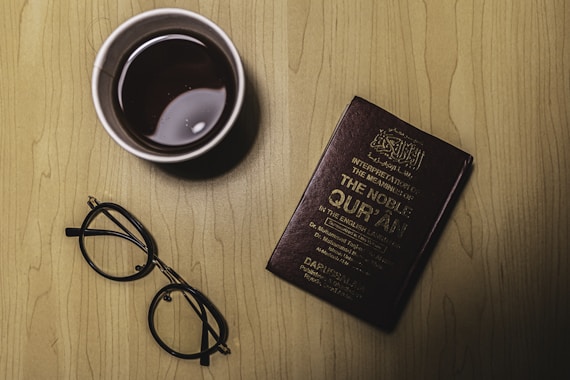black framed eyeglasses beside purple book
