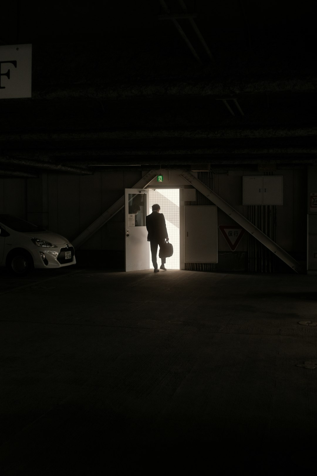 man in white t-shirt and black pants standing beside white coupe in a tunnel