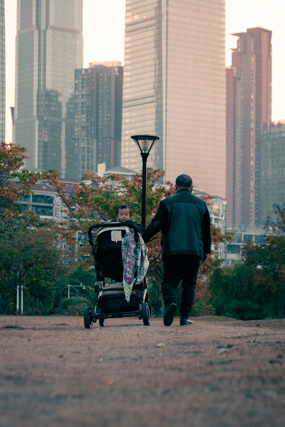 man in blue jacket and blue denim jeans holding black stroller