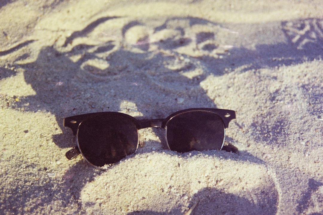 black framed sunglasses on white sand