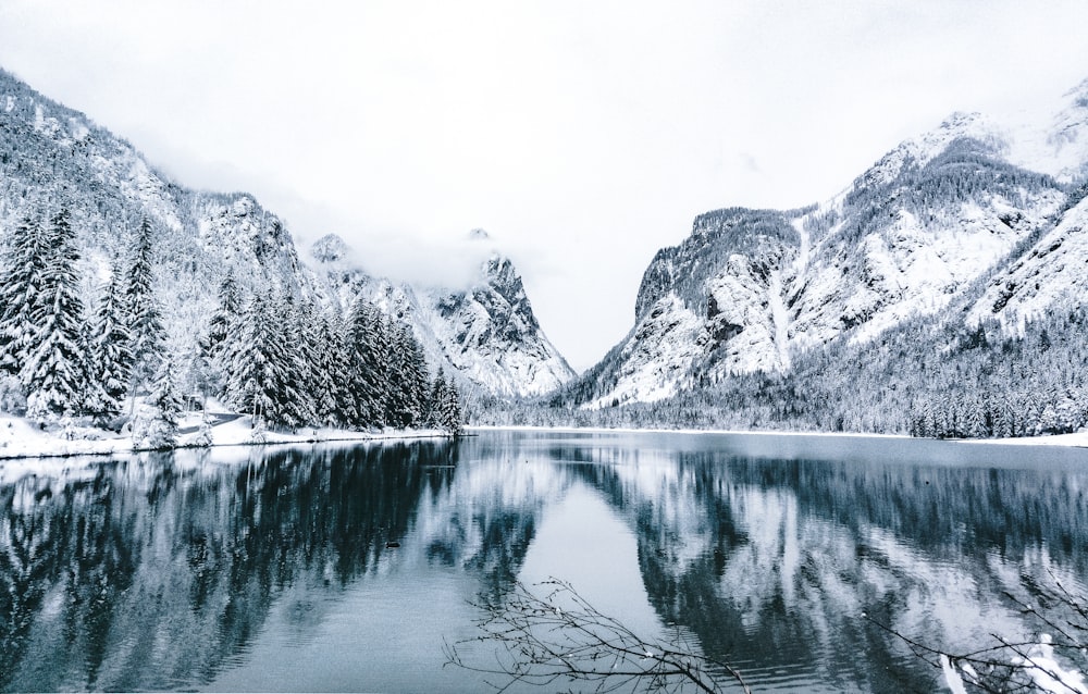 Foto en escala de grises de un lago cerca de la montaña