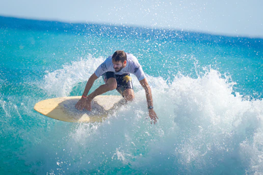 man in white t-shirt and blue shorts surfing on sea waves during daytime