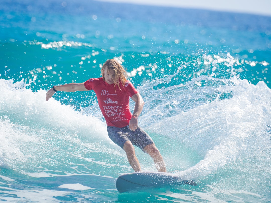 girl in red tank top and blue shorts surfing on water during daytime